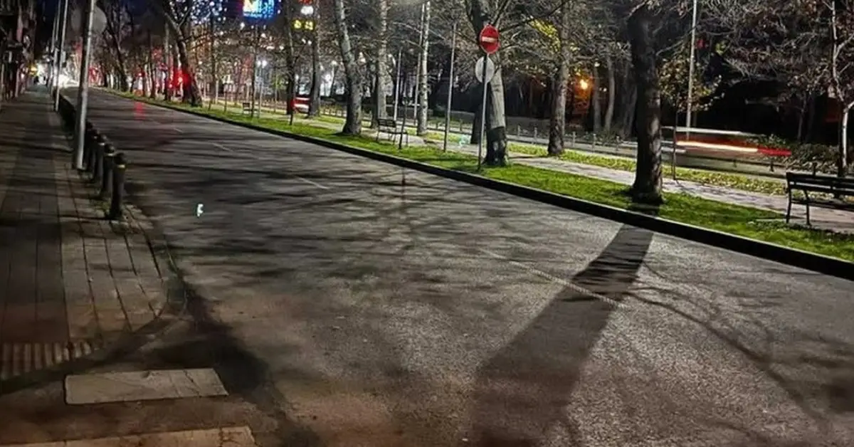 Нови арести покрай разследването за Георги Кузев: В телефон откриха видео от жесток побой над двама души Нощна панорама на пуста градска улица с дървета и дълги сенки под светлината на фенерите.