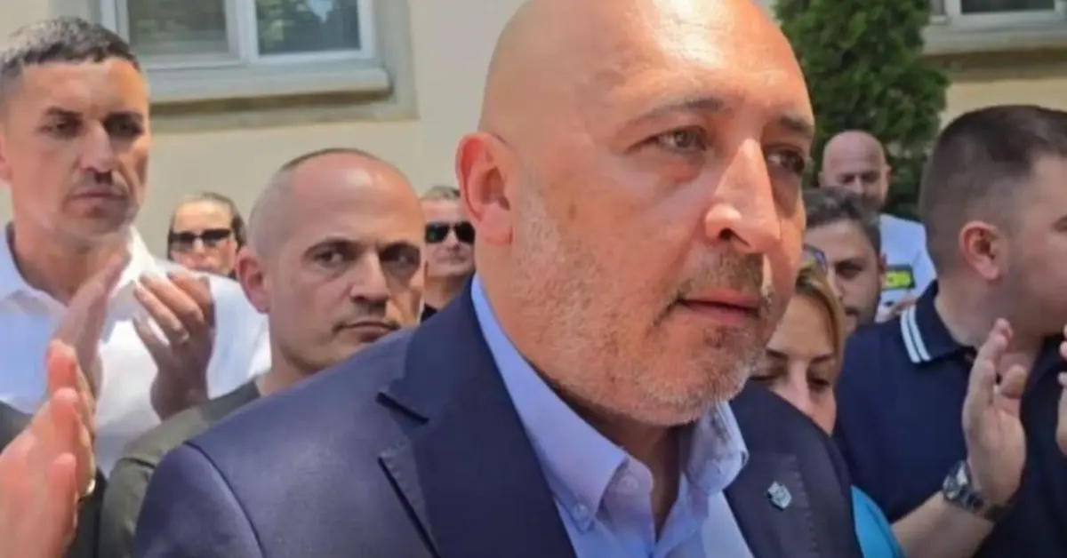 Полицейска акция в Кърджали: Задържаха кмета Ерол Мюмюн, униформени влязоха в общината и се отправиха към дома му Мъж с костюм говори пред група хора, които го слушат внимателно на открито събитие.