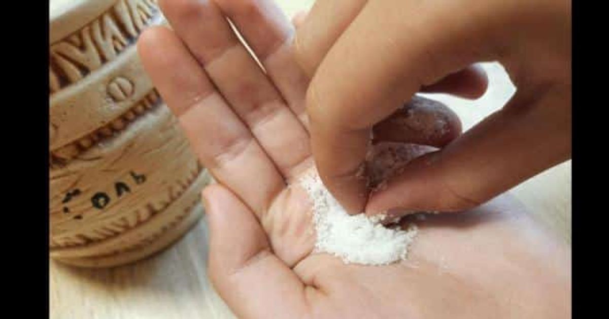Осигури си спокоен сън с магическата комбинация щипка сол и захар преди лягане, доказани ефекти! Ръце взимат бяла сол от традиционна керамична солница.