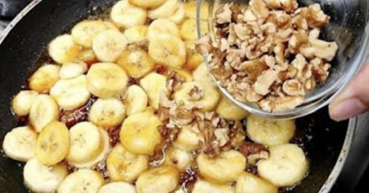 Евтин и вкусен кекс с банани и орехи Ръка добавя нарязани орехи към карамелизирани банани в тиган.