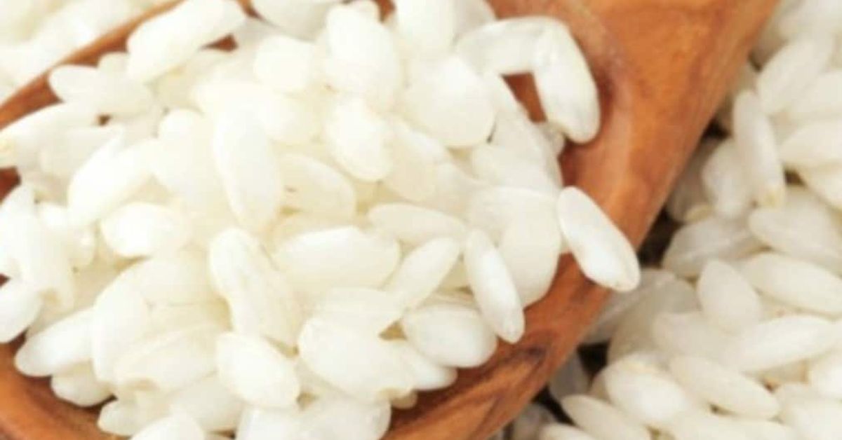 Ето как да разпознаем истинския ориз на пазара и да сме сигурни, че не сме закупили фалшив такъв Едри бели оризови зърна в дървена лъжица и разпръснати наоколо.