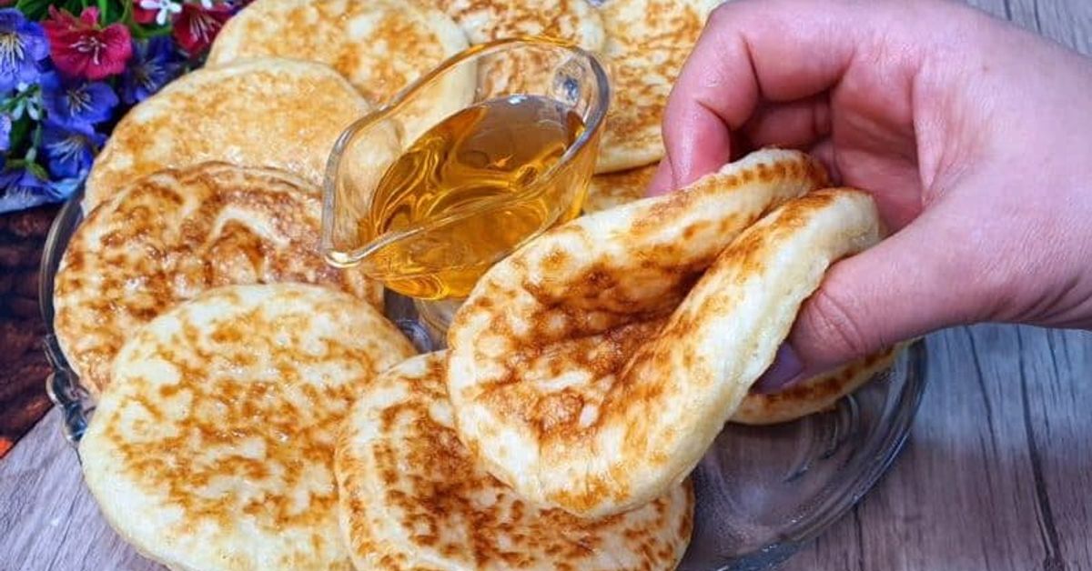 Пухкави копринени палачинки – рецептата, която винаги се получава Домашни пухкави оладки с мед, сервирани на чиния, ръка взима една.