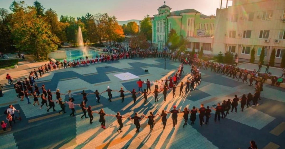 Великолепието на Ески Джумая: архитектурното бижу на България Хора танцуват традиционно българско хоро на открит площад.