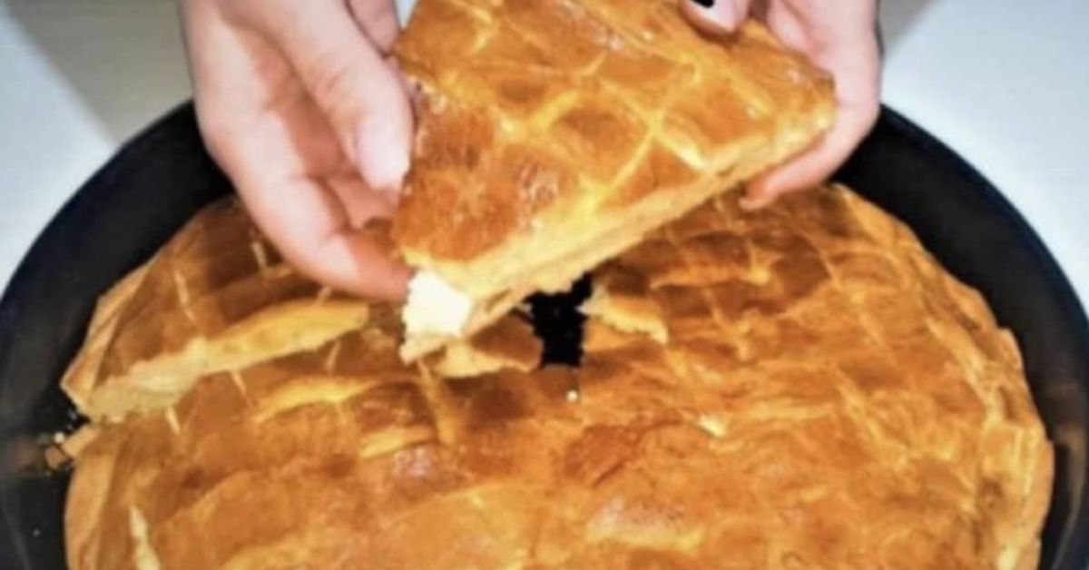 Само 1 чаша кисело мляко е нужна за тази лята баница – вкус, какъвто няма по баничарниците Ръце държат златисто парче баница със сирене, извадено от тава.