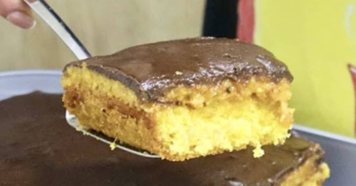 Взимам 4 яйца и правя чуден сладкиш, пръстите ще си оближеш, всяка седмица рецептата ще повтаряш! (СНИМКИ) Парче торта с жълт блат и шоколадова глазура, сервирано със шпатула.