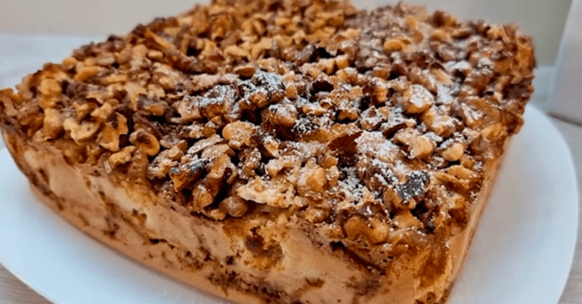 Много бърз и вкусен сладкиш с орехи и ябълки, който изглежда като от списание Апетитен десерт с орехи и пудра захар на бяла чиния.