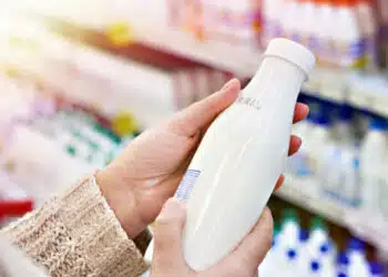 Buyer hands with a bottle of milk at the grocery store