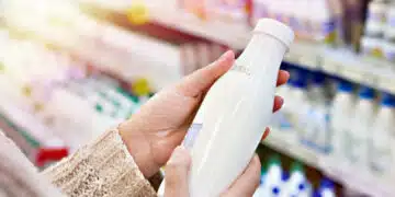 Buyer hands with a bottle of milk at the grocery store