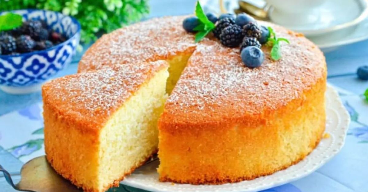 Мек и вкусен пандишпан „12 лъжички“, който ще Ви върне в детството Вкусна торта с отрязано парче, поръсена със захар, украсена с боровинки и къпини.