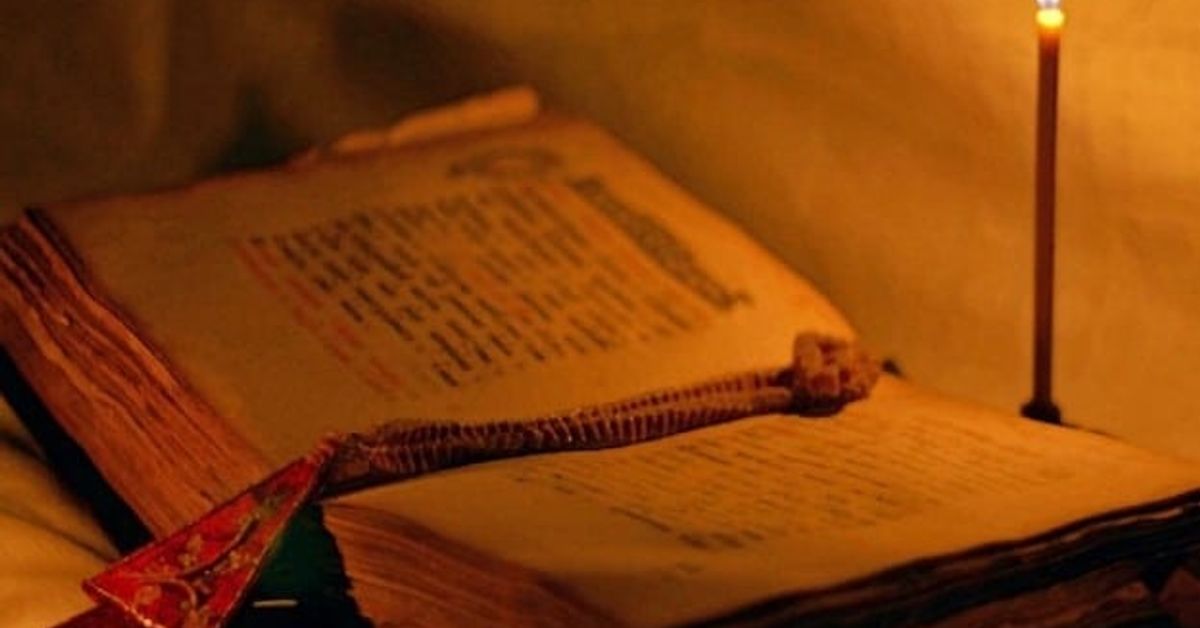 Чета молитва, винаги когато имам поредица от лош късмет и неуспехи заради лоши очи, недоброжелатели и тайни врагове Отворена стара книга с декоративен разделител и горяща свещ до нея.