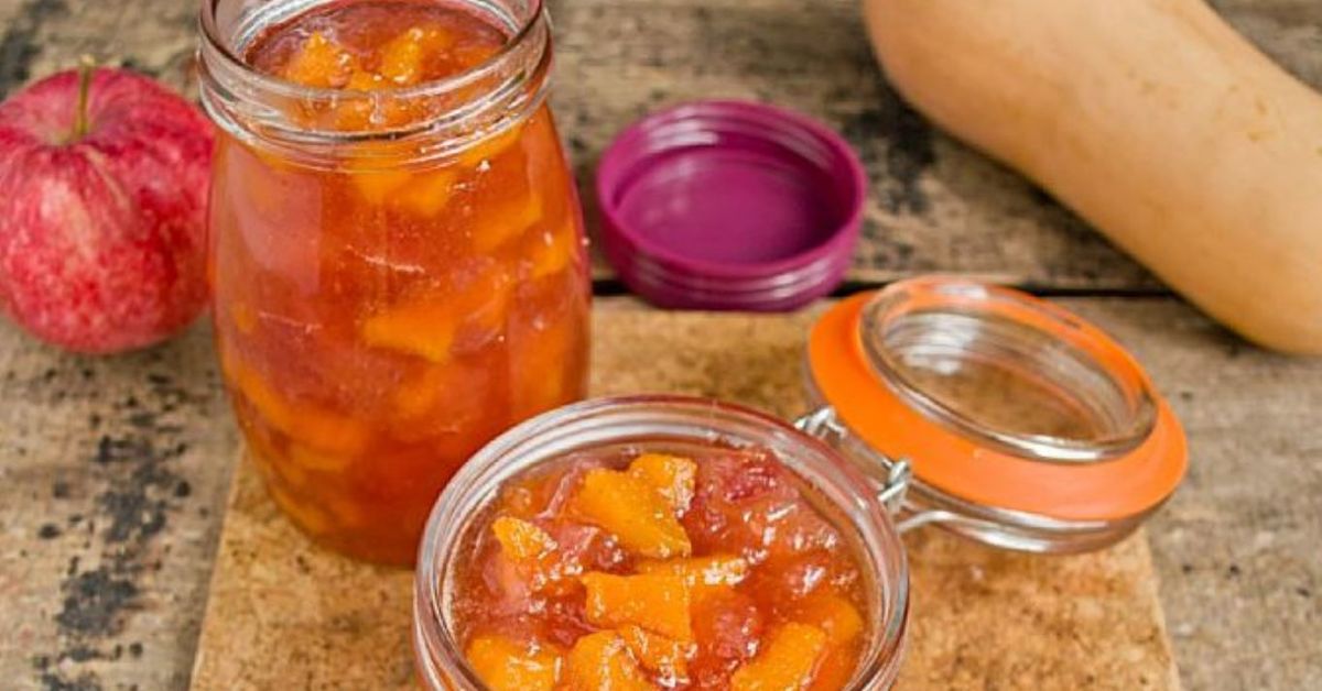 Просто смеси ябълки и тиква, за да направиш най-вкусното сладко - върви с всичко Буркани с домашно сладко от тиква и ябълка на рустикална дървена маса.