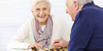 Happy senior couple playing checkers in a retirement home
