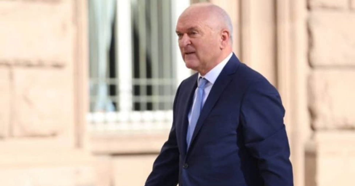 Появиха се СНИМКИ на семейството на премиера Главчев, ето ги и тях: Мъж в тъмносин костюм и светлосиня вратовръзка върви пред сграда.