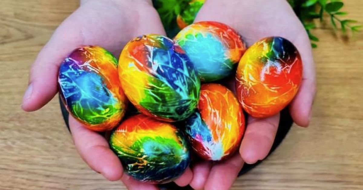 Космически яйца за Великден: лесно и бързо оцветяване със салфетки Ръце държат шарени яйца с напукан ефект в цветове на дъгата.