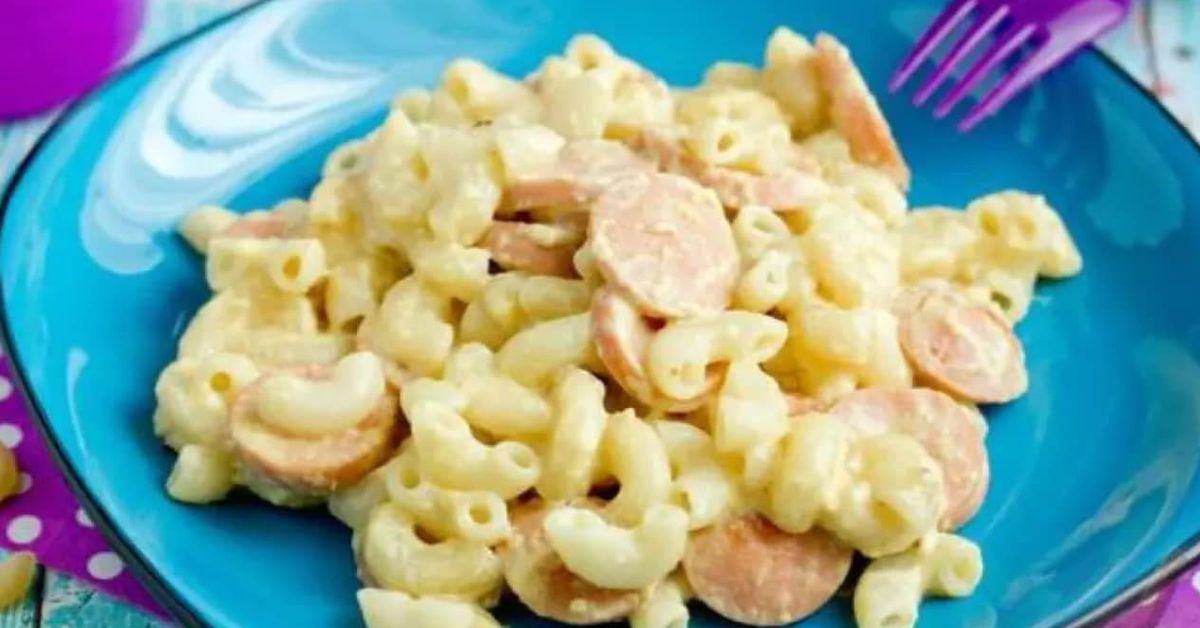 Меки и нежни макарони с колбас и сос от сметана (Рецепта) Вкусни макарони със сирене и нарязани кренвирши в синя чиния.