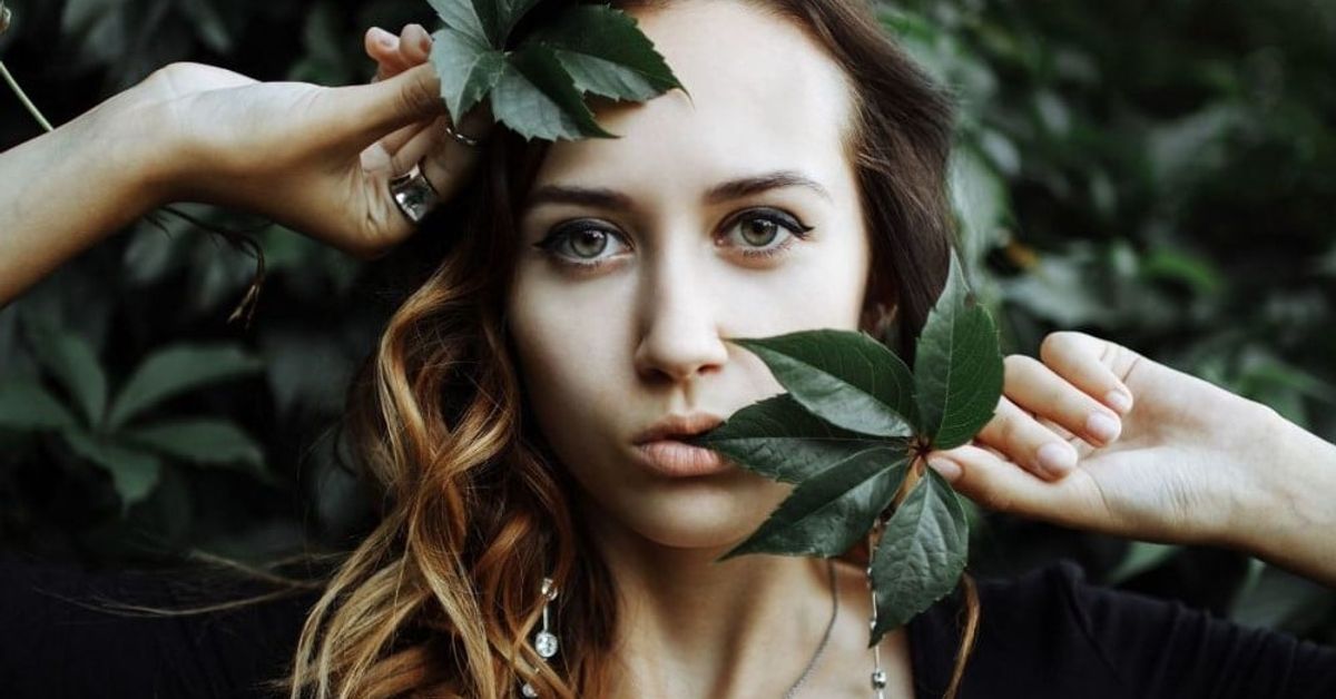Какъв празник утре - четвъртък, 25 април - всичко за този ден, какво не трябва да се прави: Портрет на млада жена с къдрава коса и зелени листа сред природата.