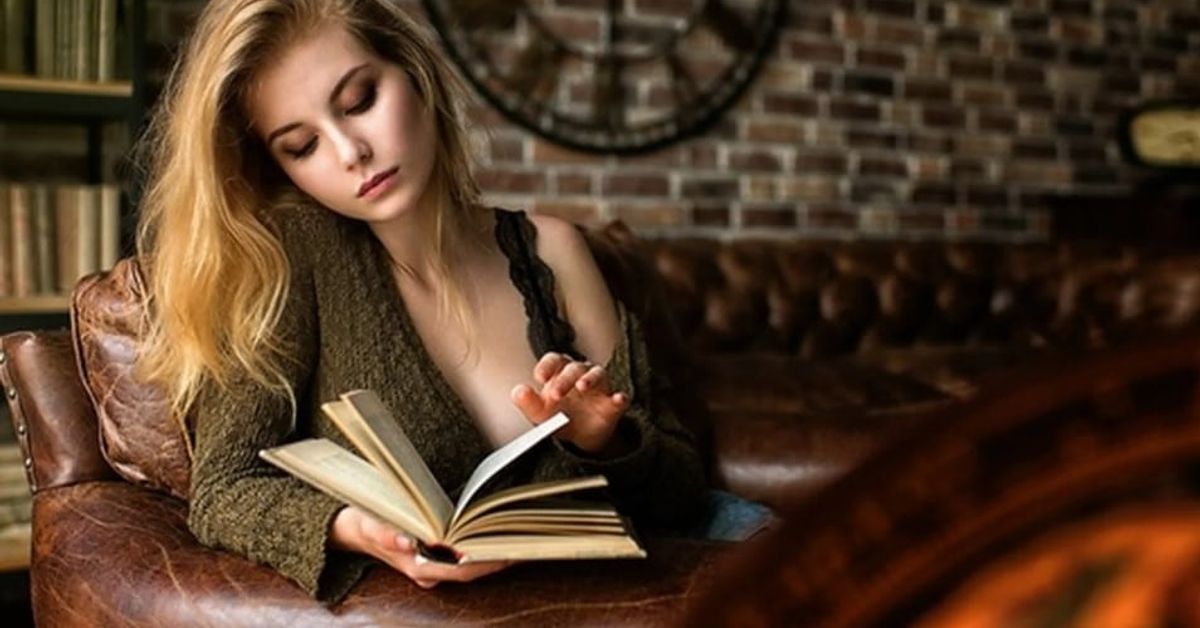 7 признака на висока интелигентност: Само няколко души притежават тези специални характеристики Млада жена с руса коса чете книга на кожен фотьойл в уютна обстановка.