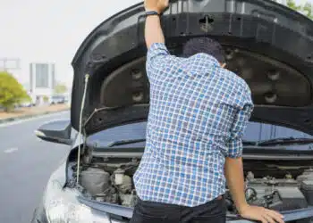mechanic wearing gloves open car hood checking car engine oil on the road after car breakdown problem.Young man maintenance, fixing trouble car accident repair at garage workshop.