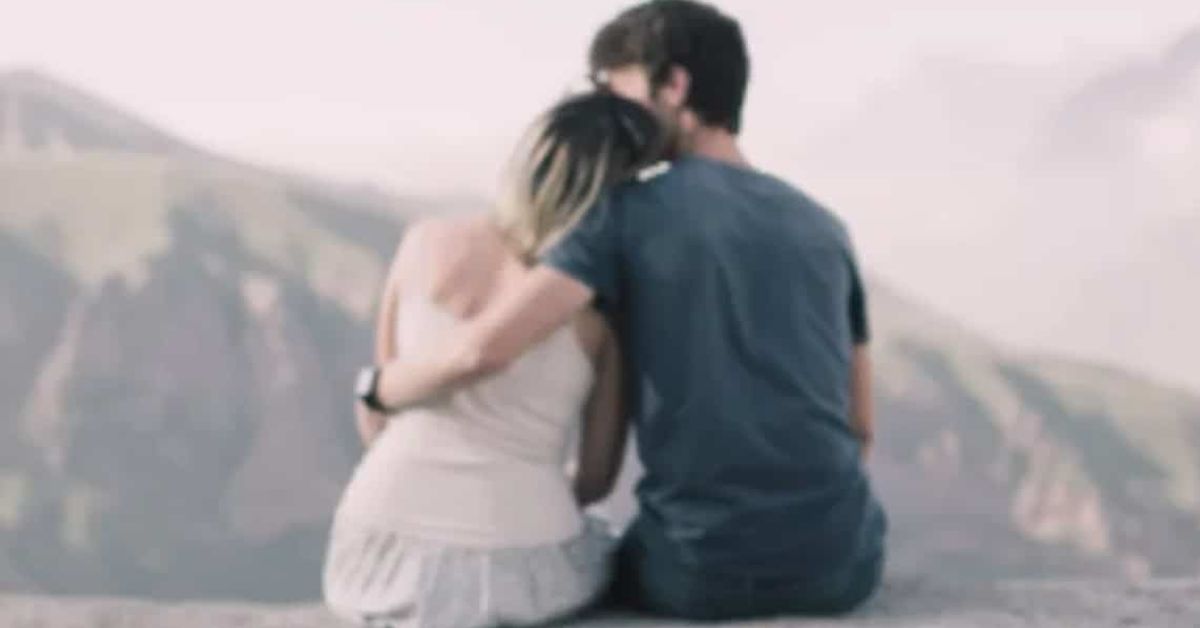 5 неща, които всяка жена иска да чуе от мъжа, когото харесва Романтична двойка седи прегърната и гледа към планински пейзаж.