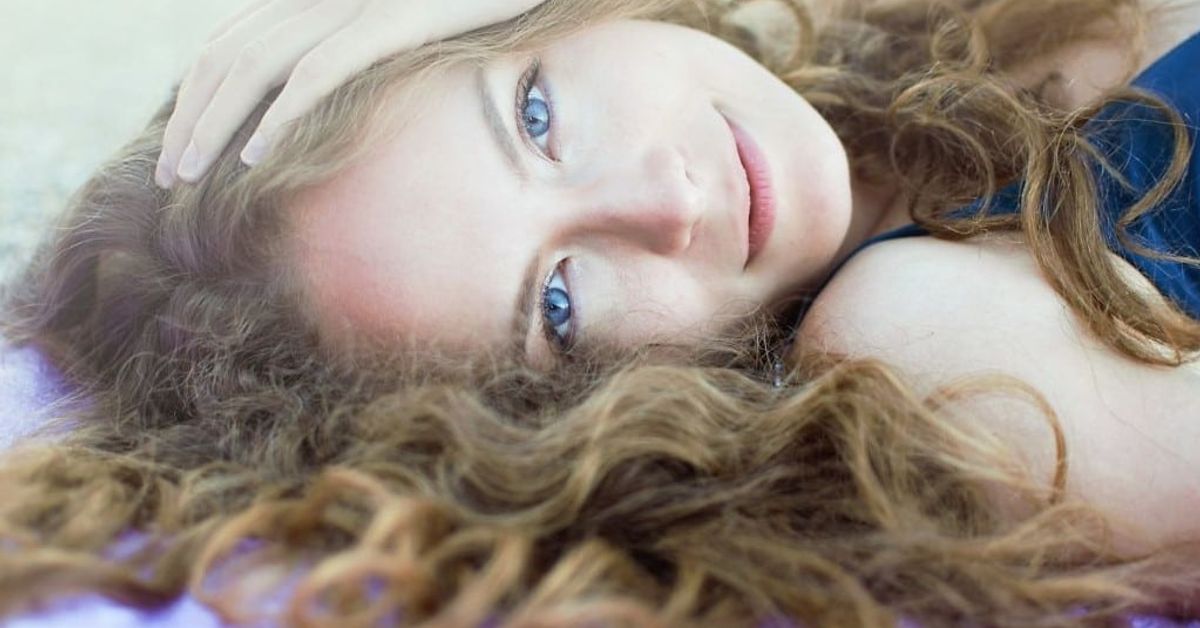 Днес, 21 юни е църковен празник – какво трябва да НЕ правим Усмихната млада жена със сини очи и къдрава коса лежи спокойно.