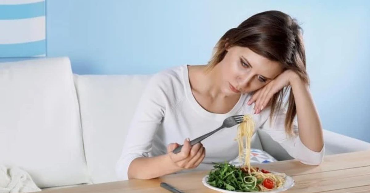 Трябва да ги избягвате! Ето кои хранителни продукти могат да предизвикат депресия у вас Тъжна жена гледа чиния със спагети и салата, седнала на маса.