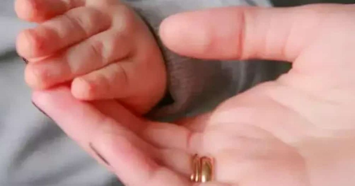 Какво децата наистина наследяват от майката: 3 доказани биологични влияния Бебешка ръка в дланта на възрастен със златни пръстени.