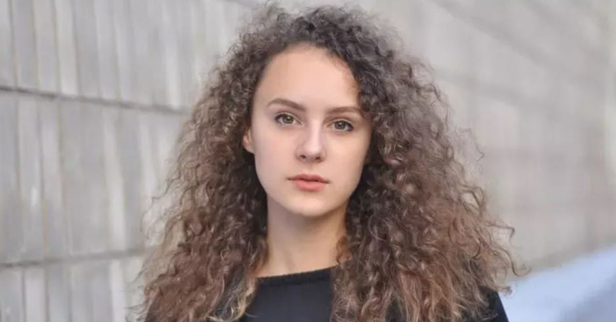 Какво отличава умната жена: тайните на харизмата и психологията на успеха Портрет на млада жена с дълга къдрава кафява коса.