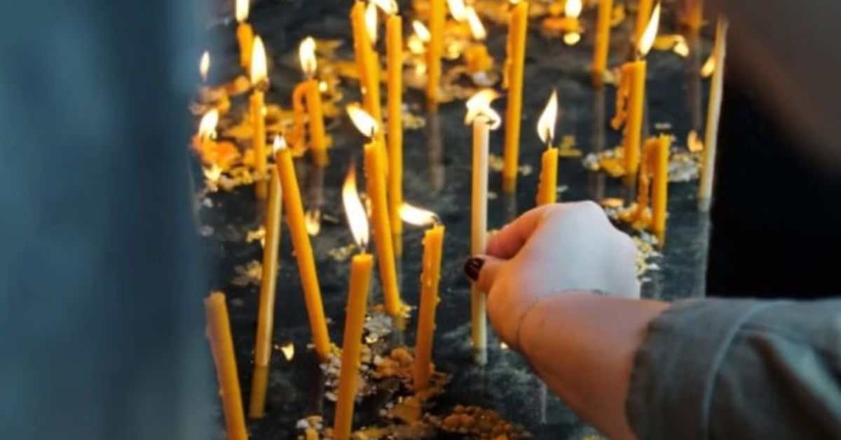 ТАЗИ СЪБОТА, 22 февруари отбелязваме Голяма Задушница - предупреждение какво НЕ се прави в този ден Ръка пали тънка жълта свещ сред десетки други запалени свещи.