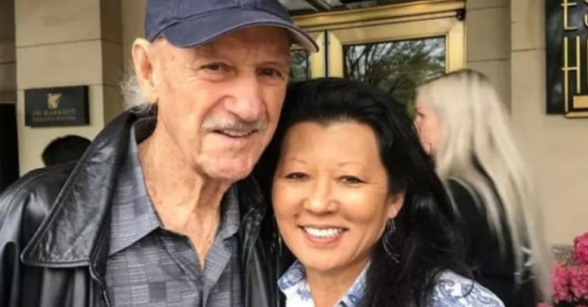 Джийн Хекман и жена му починаха, какво ще се случи с наследството от 80 милиона? Усмихнат възрастен мъж с шапка и жена позират пред хотел JW Marriott.
