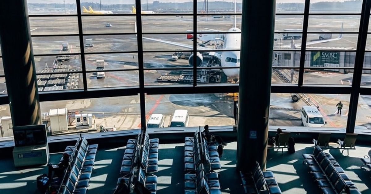 Известната авиокомпания Ryanair ще глобява пасажерите си, ако закъсняват за полет Летищен терминал с изглед към самолет на пистата и чакащи пътници.