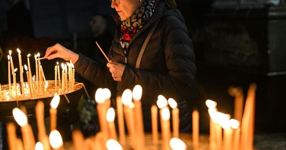 Утре 24 април е църковен празник - традиции и обичаи, които се спазват Жена пали свещ в църква, заобиколена от множество горящи свещи.