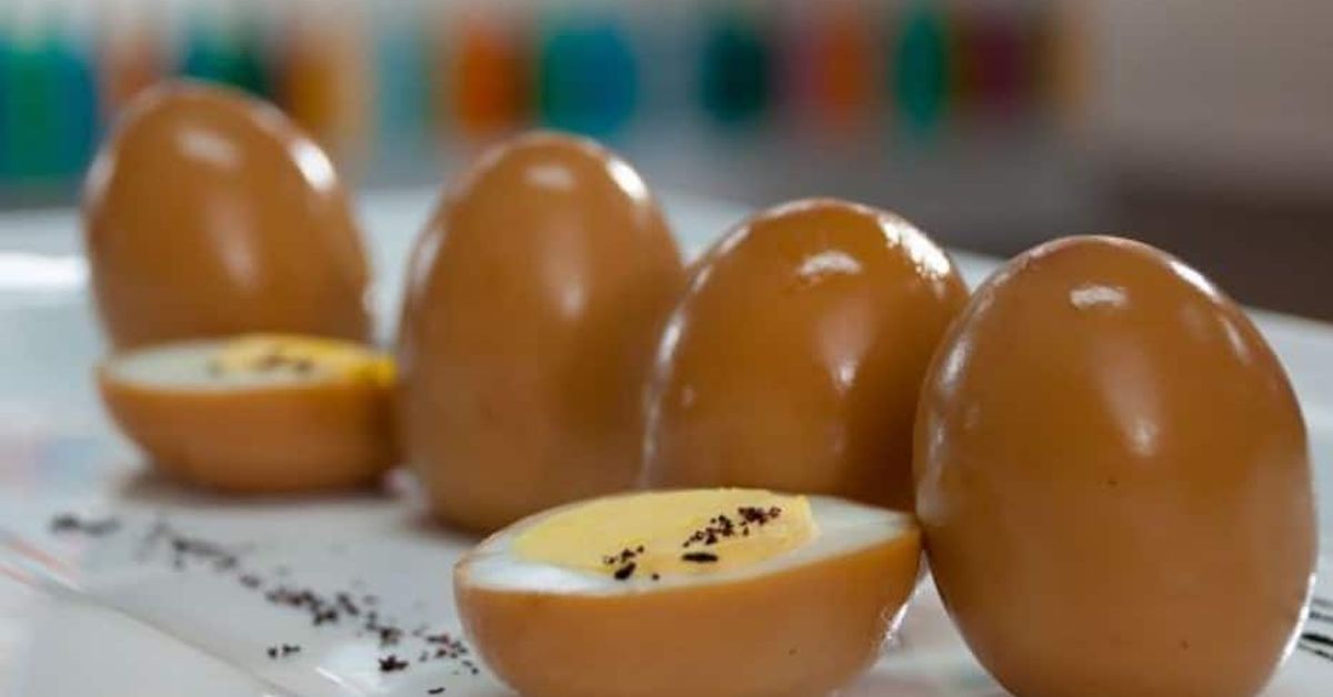 Пикантни корейски мариновани яйца: вкусно предястие, което ще пасне на всяка маса Кафяви варени яйца, някои разрязани наполовина, поднесени на бяла чиния.