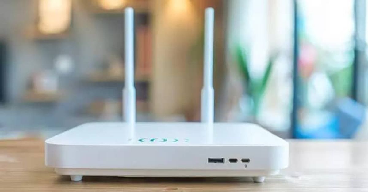 Какво означава, ако рутерът ви свети в червено през нощта Бял Wi-Fi рутер с две антени на дървена маса в домашен интериор.