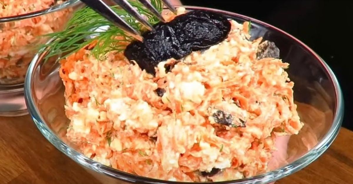 Необичайна салата с моркови, извара и сини сливи. Вкусна и здравословна: Салата от моркови, сирене и сини сливи, гарнирана с копър във стъклена купа.