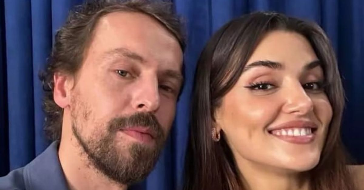 Изглеждат добре: Ханде Ерчел и Метин Акдюлгер споделят снимки зад кулисите на филма „Два свята, едно желание“ Мъж с брада и усмихната жена позират за снимка пред син фон.