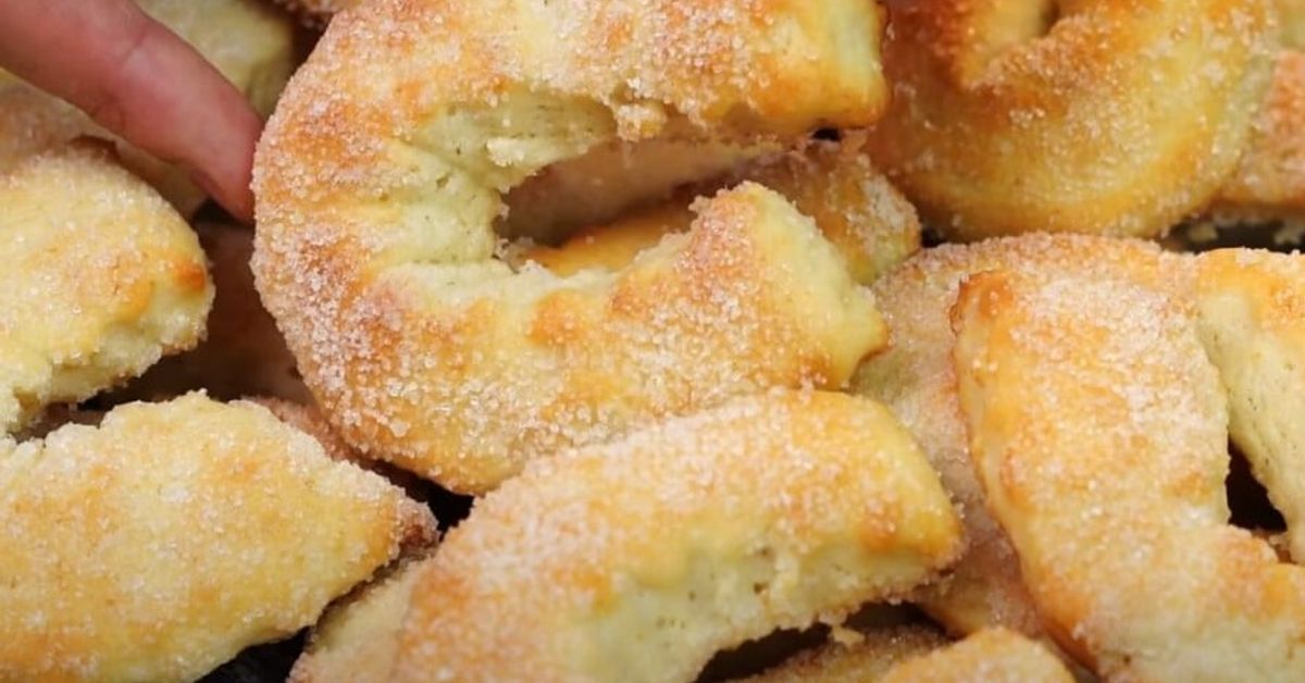 Една проста и бърза рецепта за домашни бисквитки: готвим без излишни затруднения. Минимум съставки - максимален вкус! Златисти сладки, поръсени със захар, едната е счупена, показваща мека вътрешност.