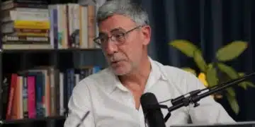 Мъж с бяла риза и микрофон.