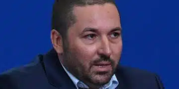 Мъж в тъмен костюм на фон.
