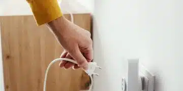 Ръка държи щепсел за контакт.
