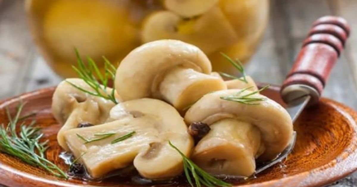 Мариновани печурки с проста рецепта: вкусни само за няколко часа Мариновани гъби печурки с розмарин, сервирани на дървена чиния.