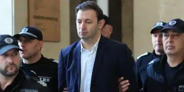 Задържан мъж, охраняван от полиция.