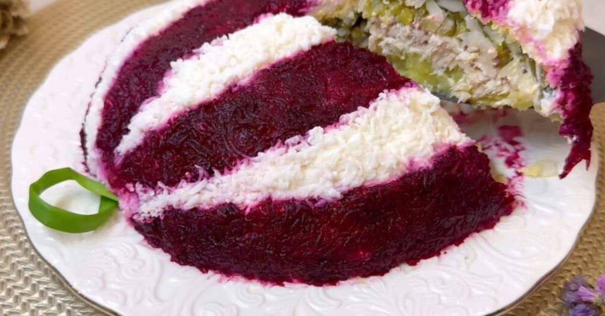 Салата „Коледна украса“ за Нова година 2026 – лесна, красива и много вкусна Апетитна многослойна салата с червено цвекло, майонеза и риба, сервирана на чиния.