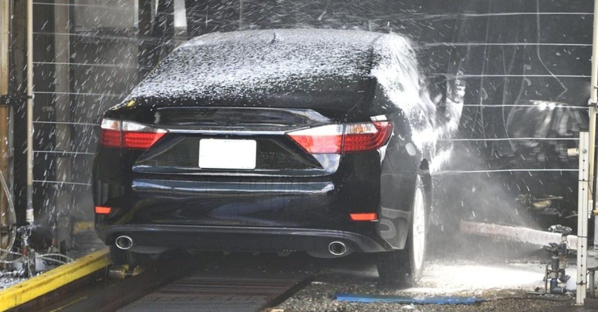 Автоексперт препоръчва: Автомивка на самообслужване само при над 10 градуса Черна кола преминава през автоматична автомивка, обливана с вода и пяна.