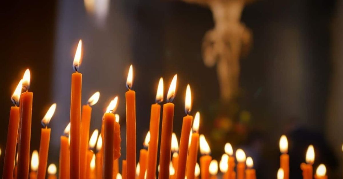 Църковният празник на 3 юни идва с важно предупреждение Запалени оранжеви свещи в църква, с размазан кръст на фона.