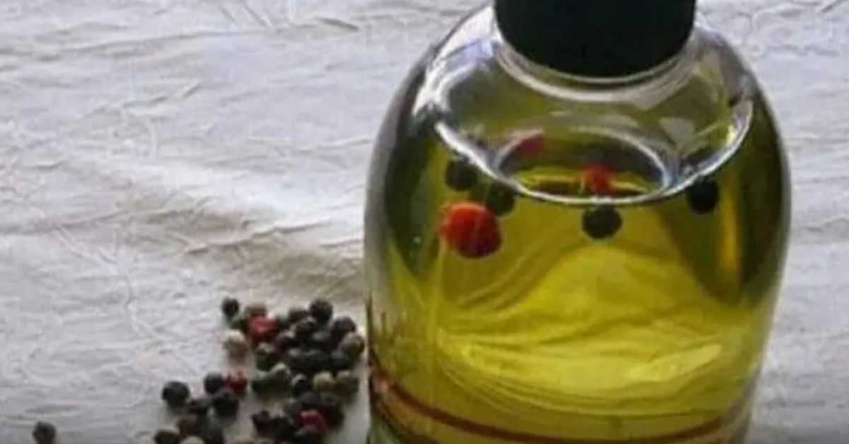 Масло, за което се смята, че подпомага прочистването от пикочна киселина Бутилка зехтин с черен и червен пипер, до купчина шарен пипер.