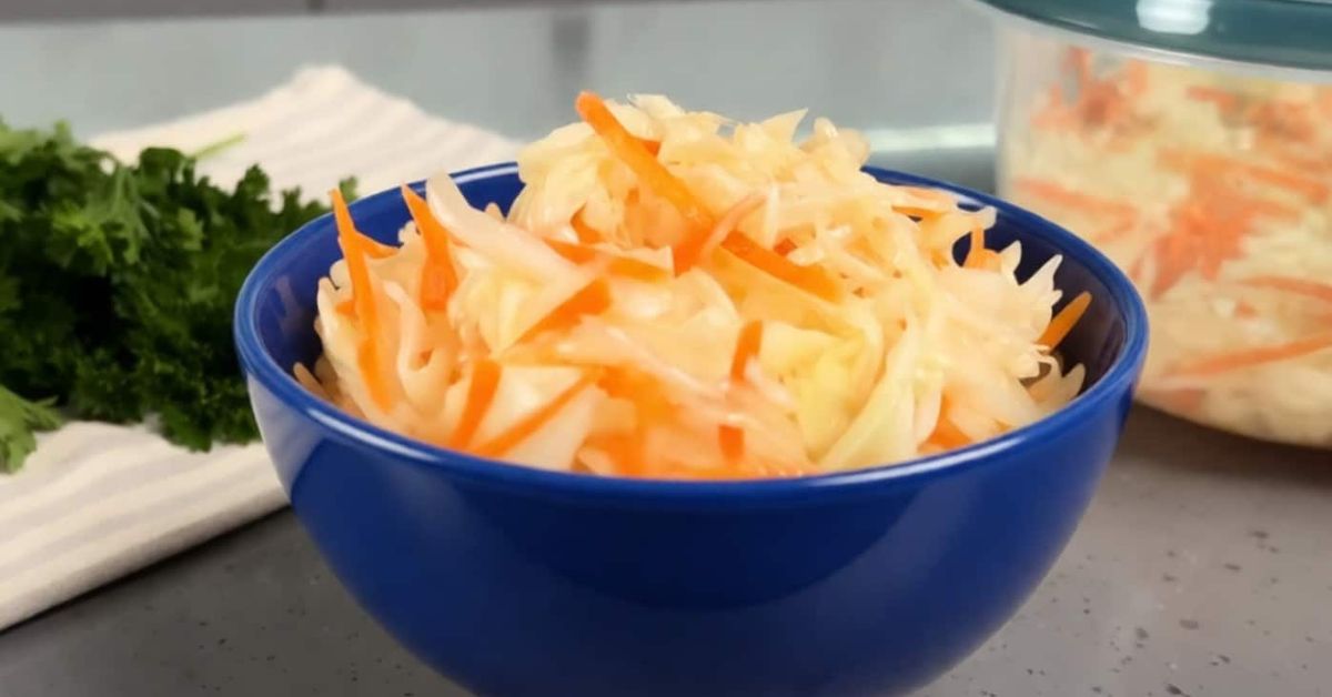 Вкусна и свежа салата „Столовски“ – класическа домашна рецепта от зеле Синя купа с кисело зеле и моркови, до нея свеж магданоз.