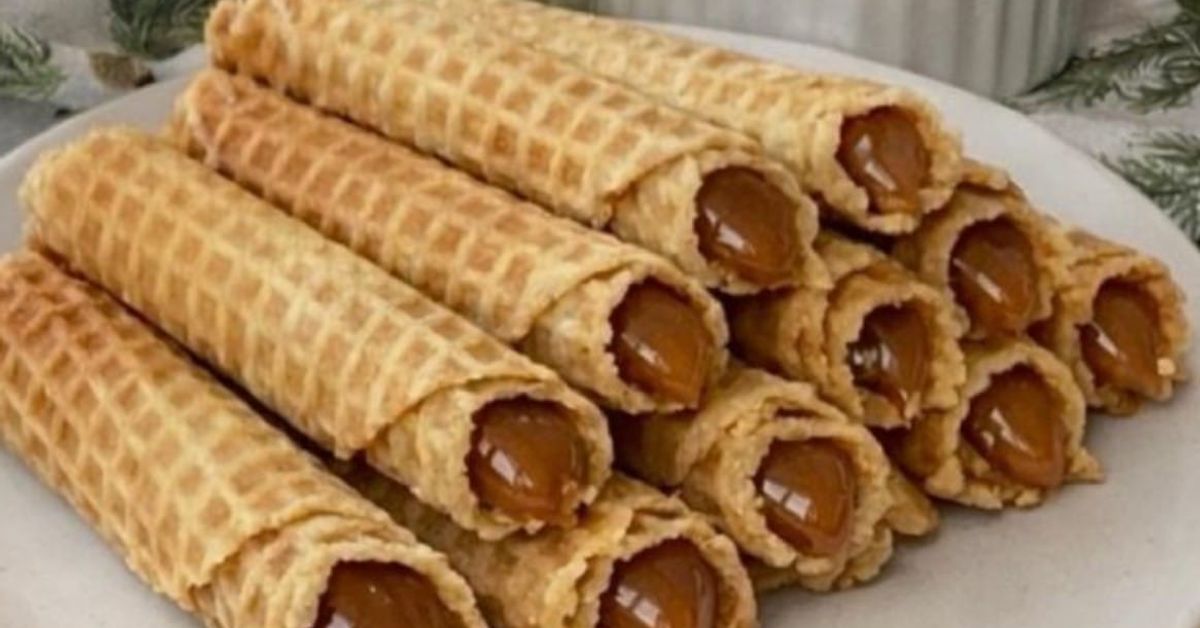 Вафлени рулца с кондензирано мляко: вкус от детството, който е лесно да се пресъздаде у дома Вафлени рулца с карамелен пълнеж, подредени на бяла чиния.