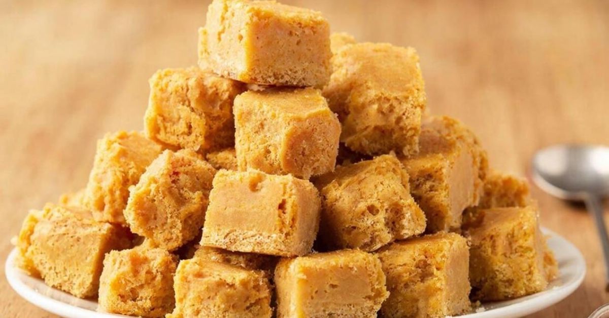 Домашна халва от слънчогледови семки – натурален вкус без излишни добавки Купчина златистокафяви квадратни сладкиши или фъдж на бяла чиния.