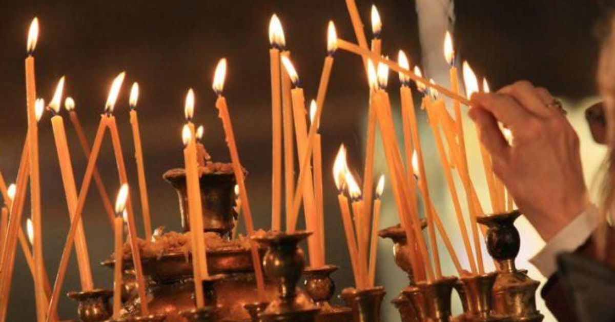 Петдесетница е! Ден на вяра, надежда и благословия за дома и семейството Ръка запалва тънка свещ сред много горящи свещи в църква.