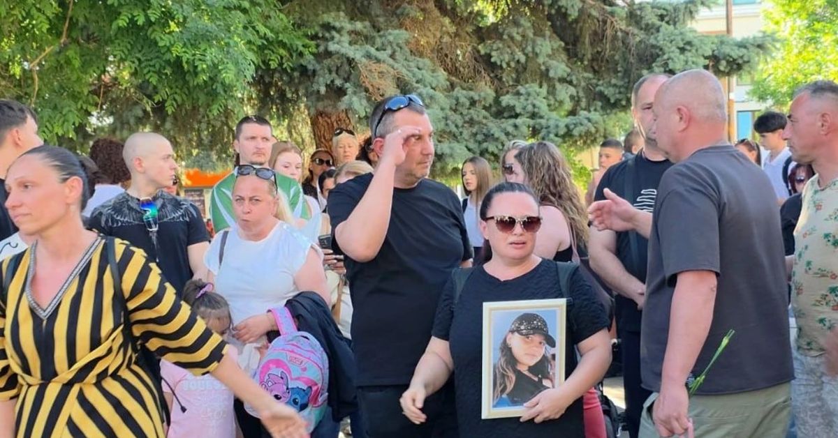 Благоевград бе разтърсен от думите на един почернен баща: 7 часа никой не е реагирал.. човеци ли сме или? Група хора на открито, жена държи снимка на момиче на възпоменателно събитие.
